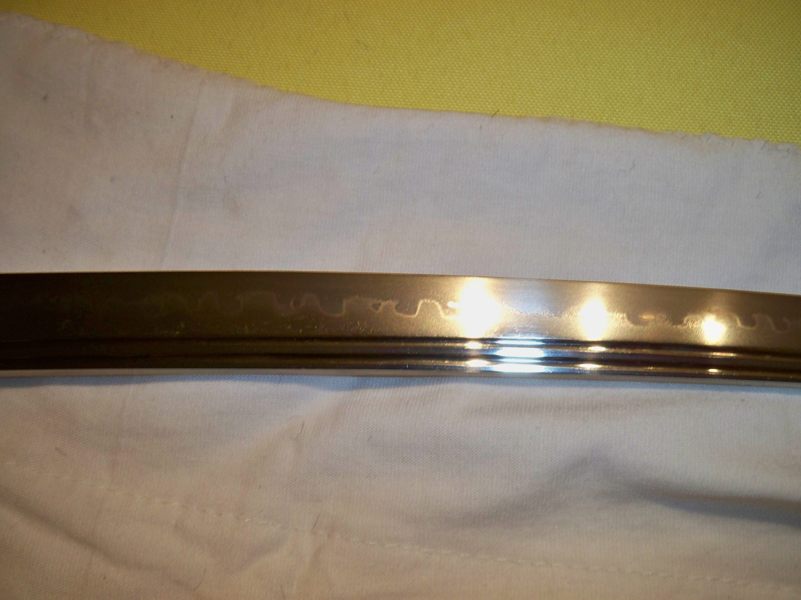 Close-up de uma lâmina de katana mostrando a distinta linha de temperamento hamon e o groove bo-hi