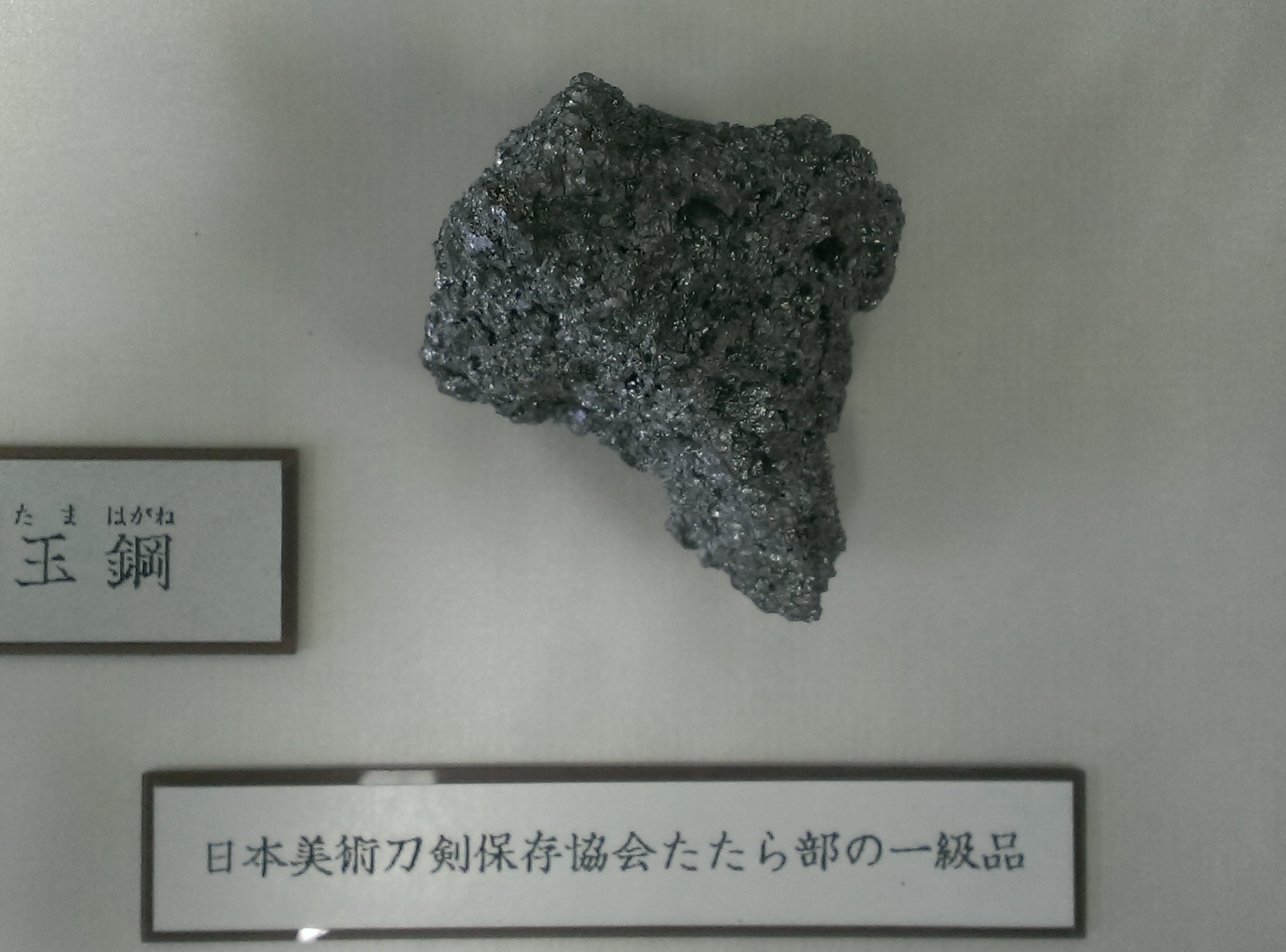 Uma flor de aço tamahagane quebrada mostrando a estrutura de carbono cristalina usada para avaliar a qualidade do forjamento de espadas japonesas